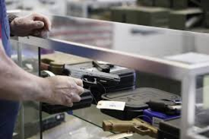 Man reaching into glass case to verify gun inventory.