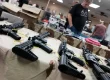 A busy gun show booth with vendors showcasing firearms and gear, while customers browse and transact using mobile sales technology.