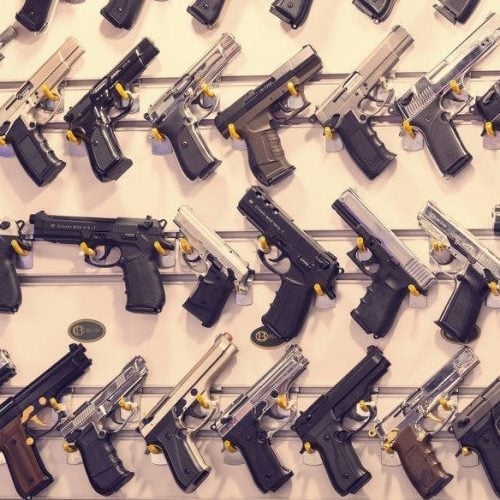 Handgun display wall organized with yellow safety locks and metal brackets, managed by RapidGunSystems firearm inventory software.