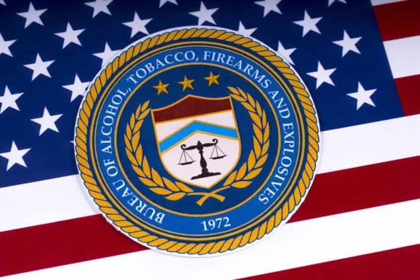 ATF seal with scales of justice, stars, laurel branches, and 1972, prominently centered on a US flag—key for electronic bound book for gun stores.