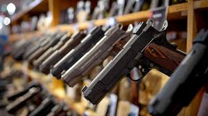 Handguns neatly lined on a rack in a gun store with wooden shelves—perfect inventory for shooting range management software users and Vendor Catalog Integrations for Gun Stores